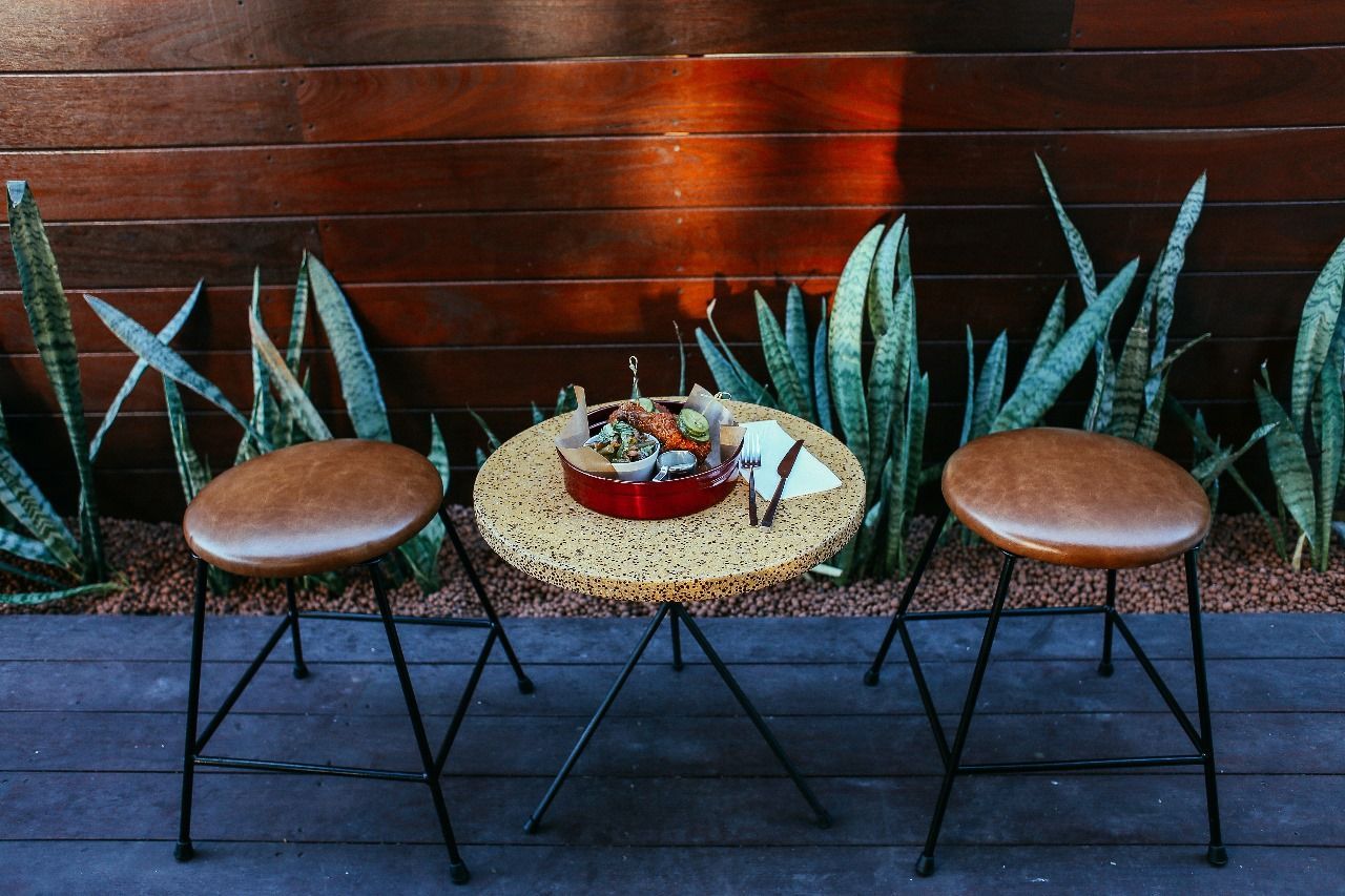 A table with two stools in front of a wooden wall