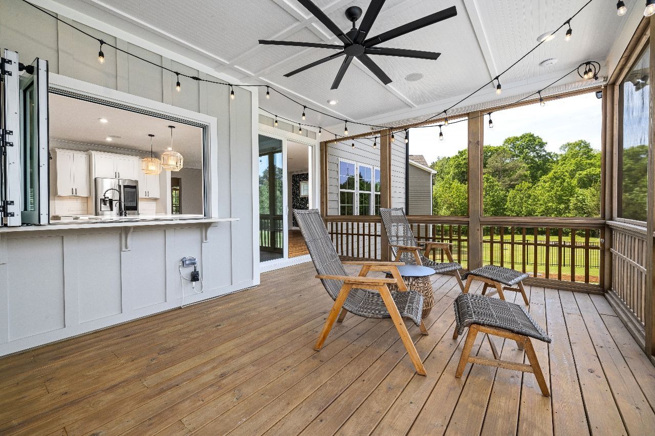 A screened in porch with chairs and a ceiling fan.