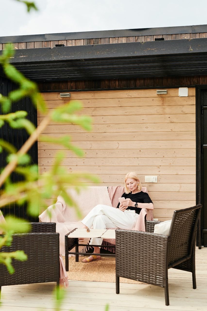 A woman is sitting on a couch on a patio.