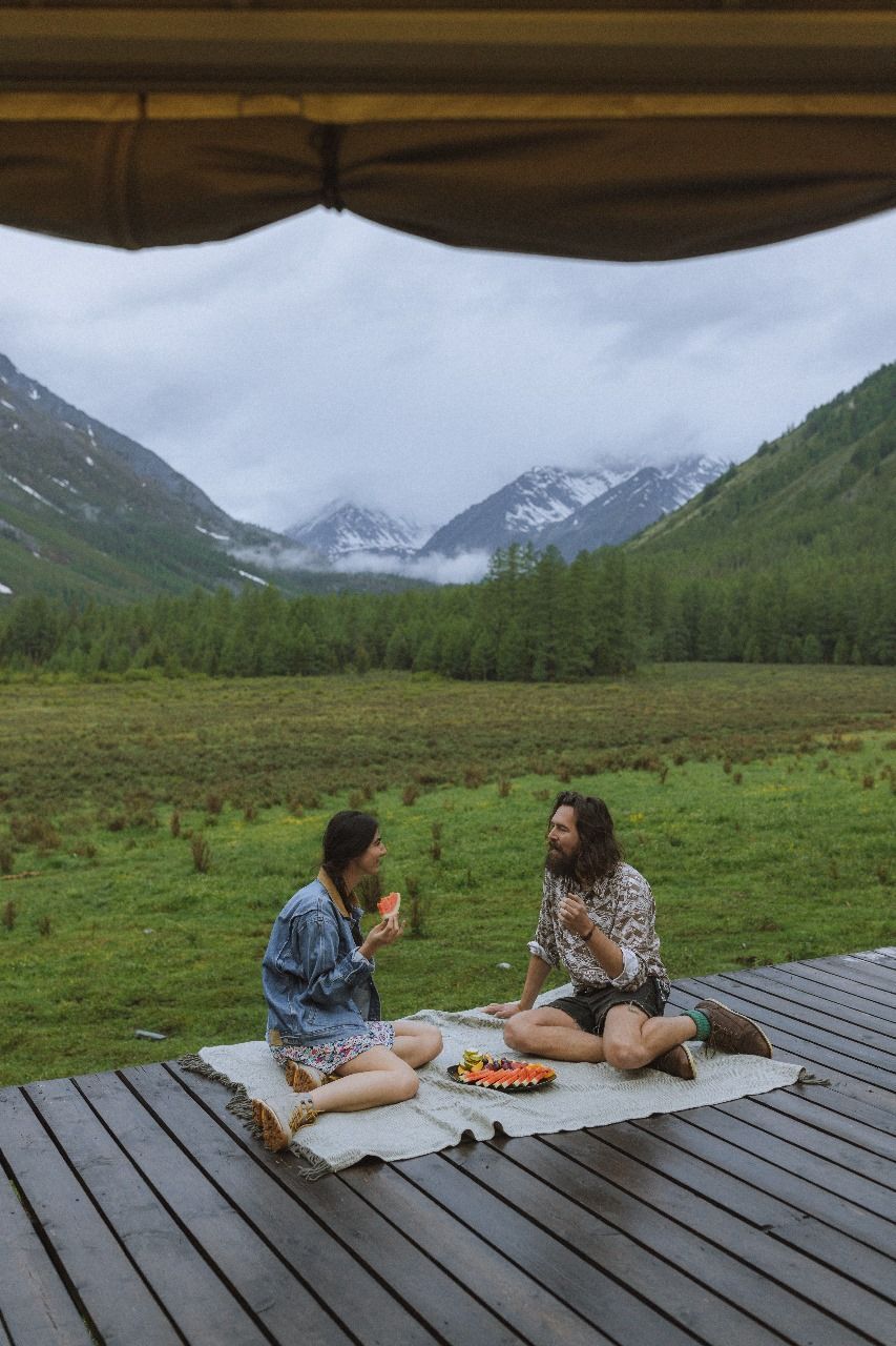 A man and a woman are having a picnic on a wooden deck.