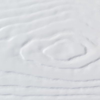 A close up of a white blanket with a swirl pattern on it.