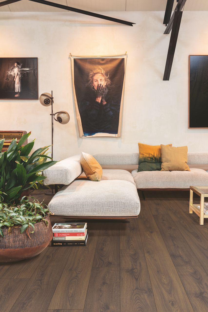 A living room with a couch , table , and paintings on the wall.