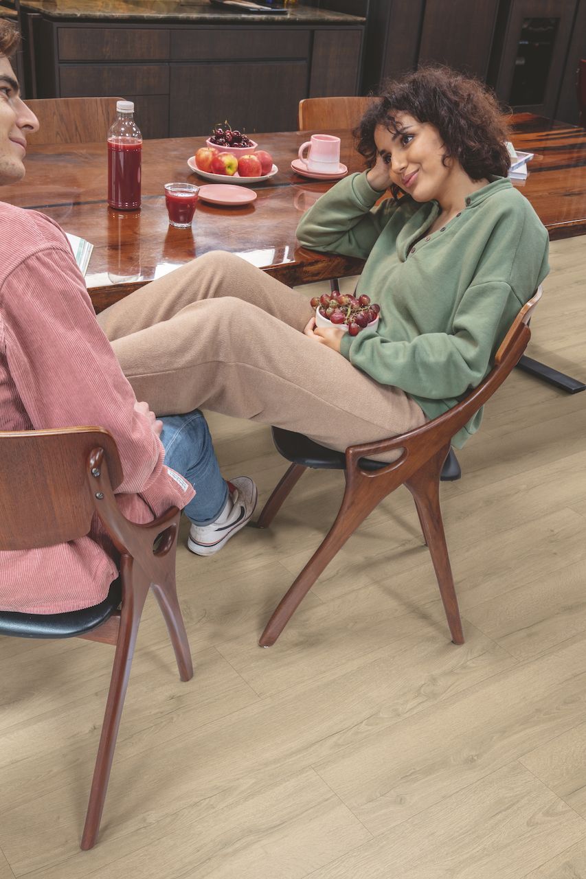 A man and a woman are sitting at a table eating grapes.