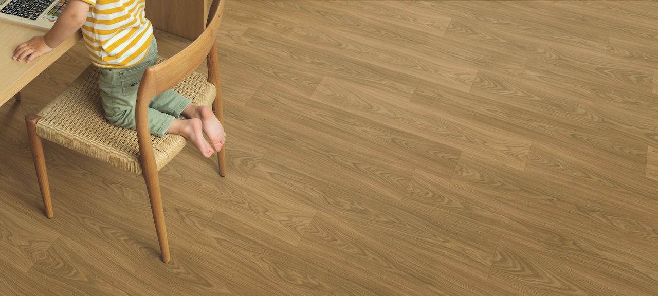 A child is sitting on a chair in front of a desk with a laptop.