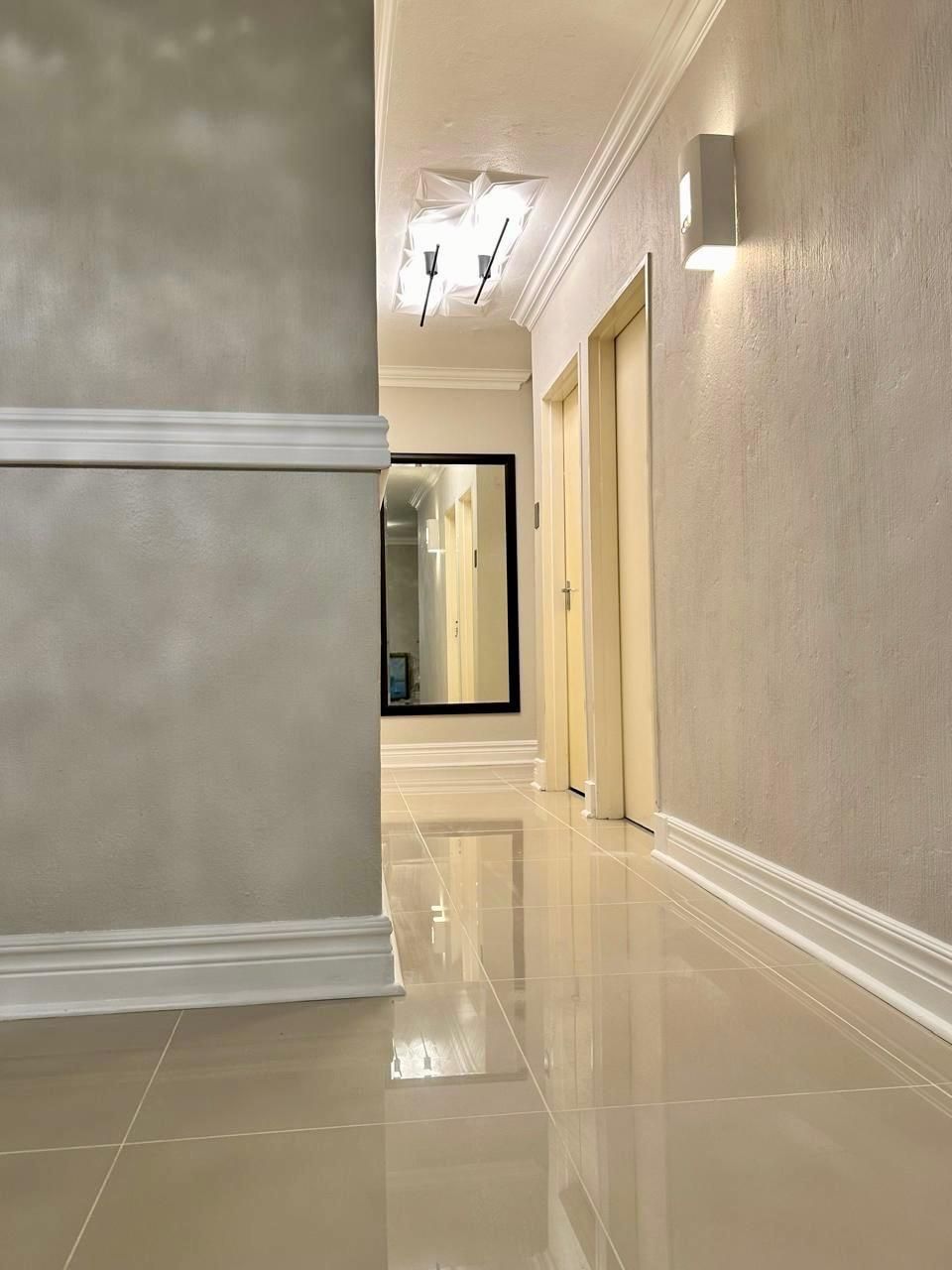 A long hallway with a mirror on the wall and a light on the ceiling.