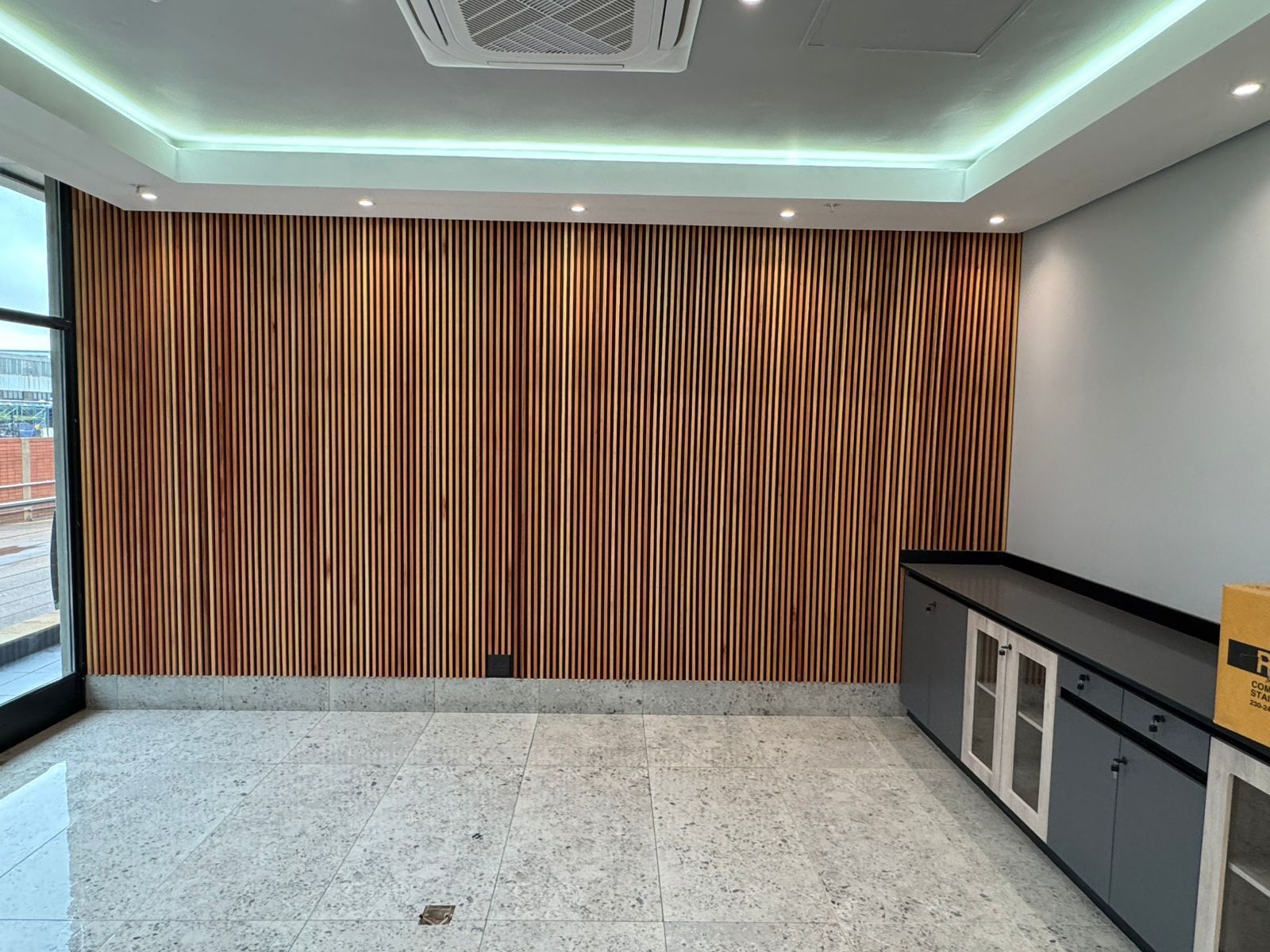 An empty room with a wooden wall and a ceiling fan.