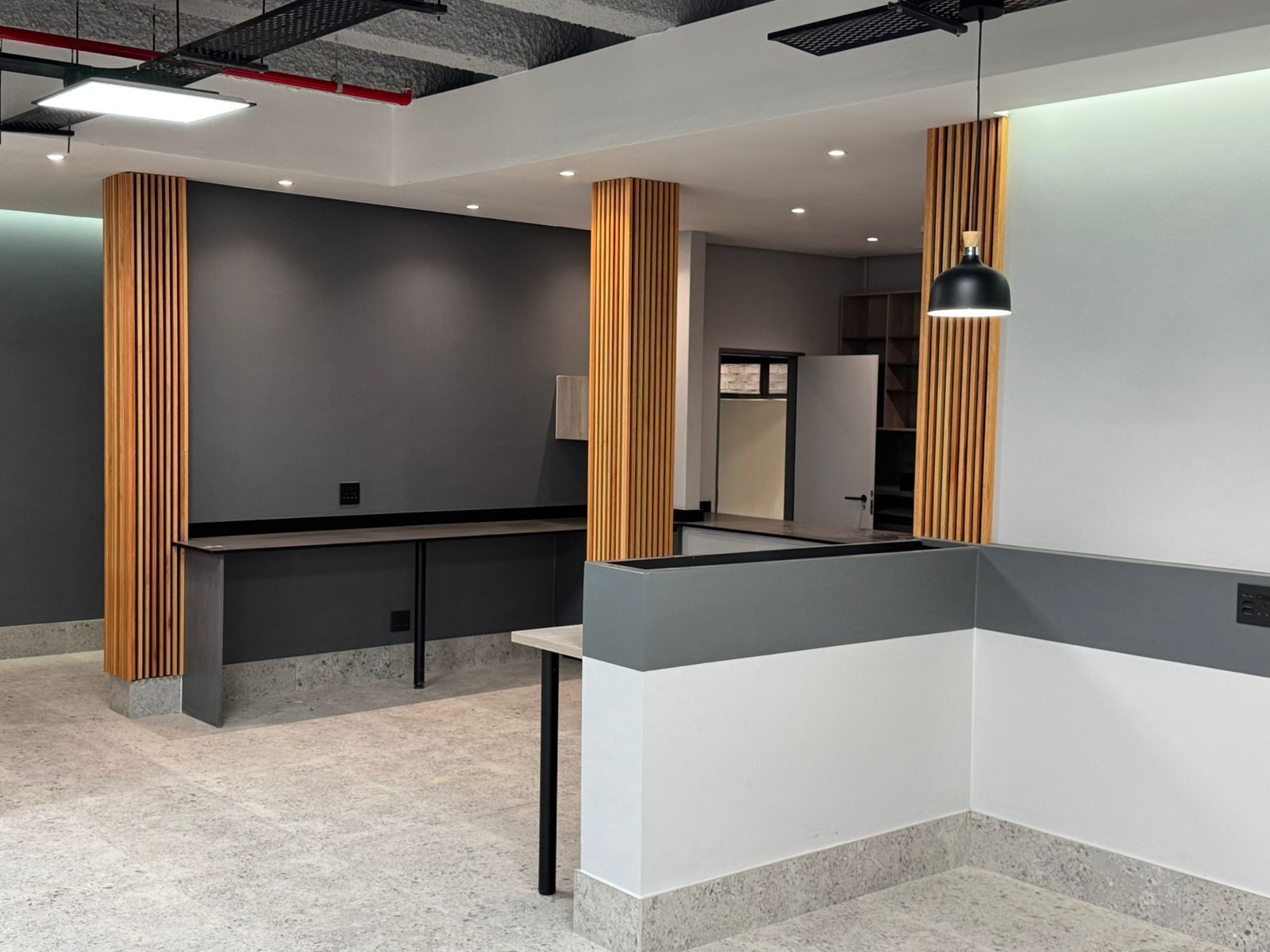 An empty room with a table and a lamp hanging from the ceiling.