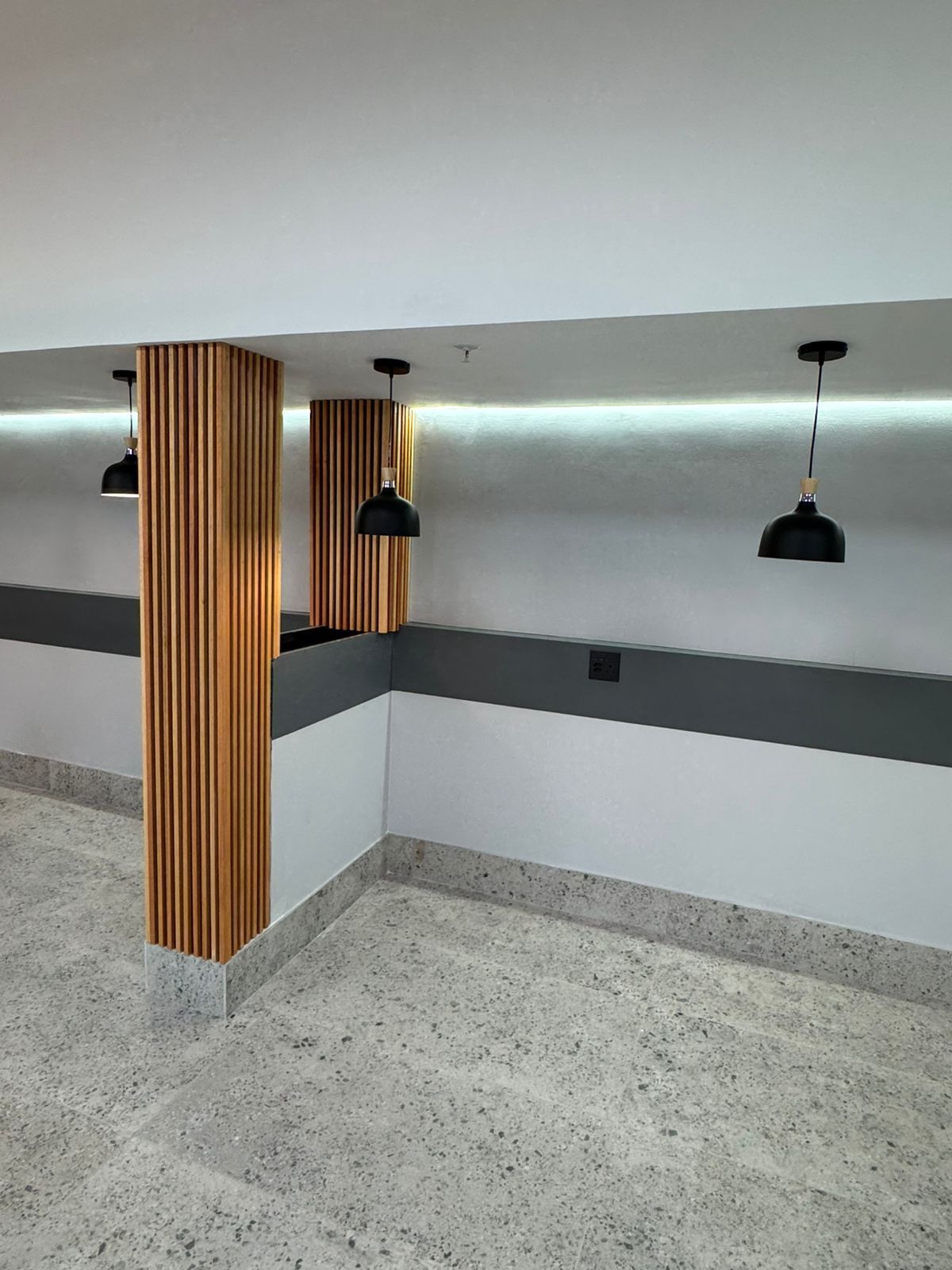 An empty room with a wooden pillar and lamps hanging from the ceiling.