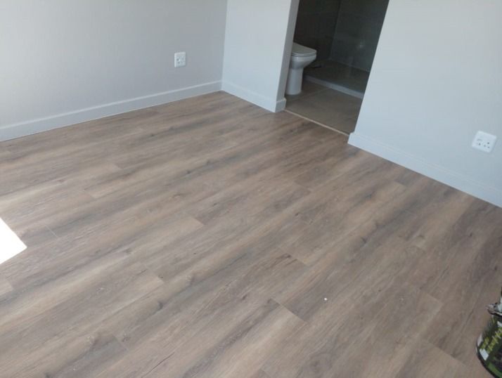 A room with a wooden floor and a toilet.