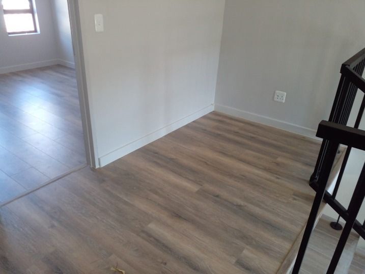 An empty room with a wooden floor and stairs