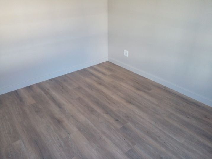 An empty room with a wooden floor and white walls.