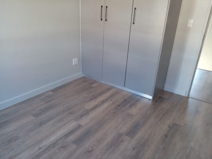 A bedroom with a wooden floor and a closet.