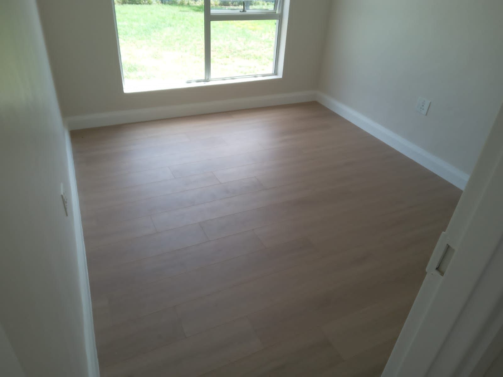 An empty room with a wooden floor and a window
