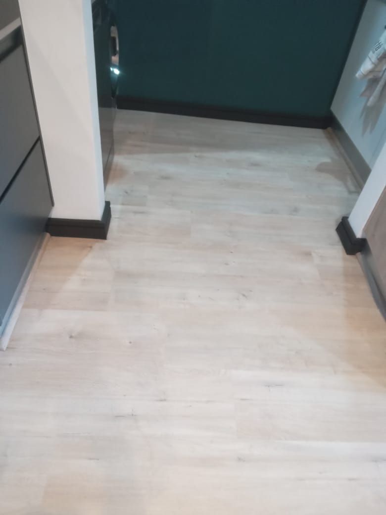 A kitchen with a white wooden floor and a green door.