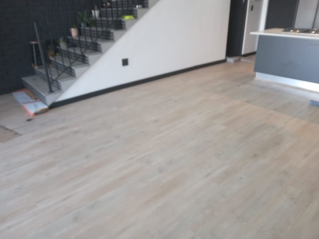 A room with a wooden floor and stairs in the background