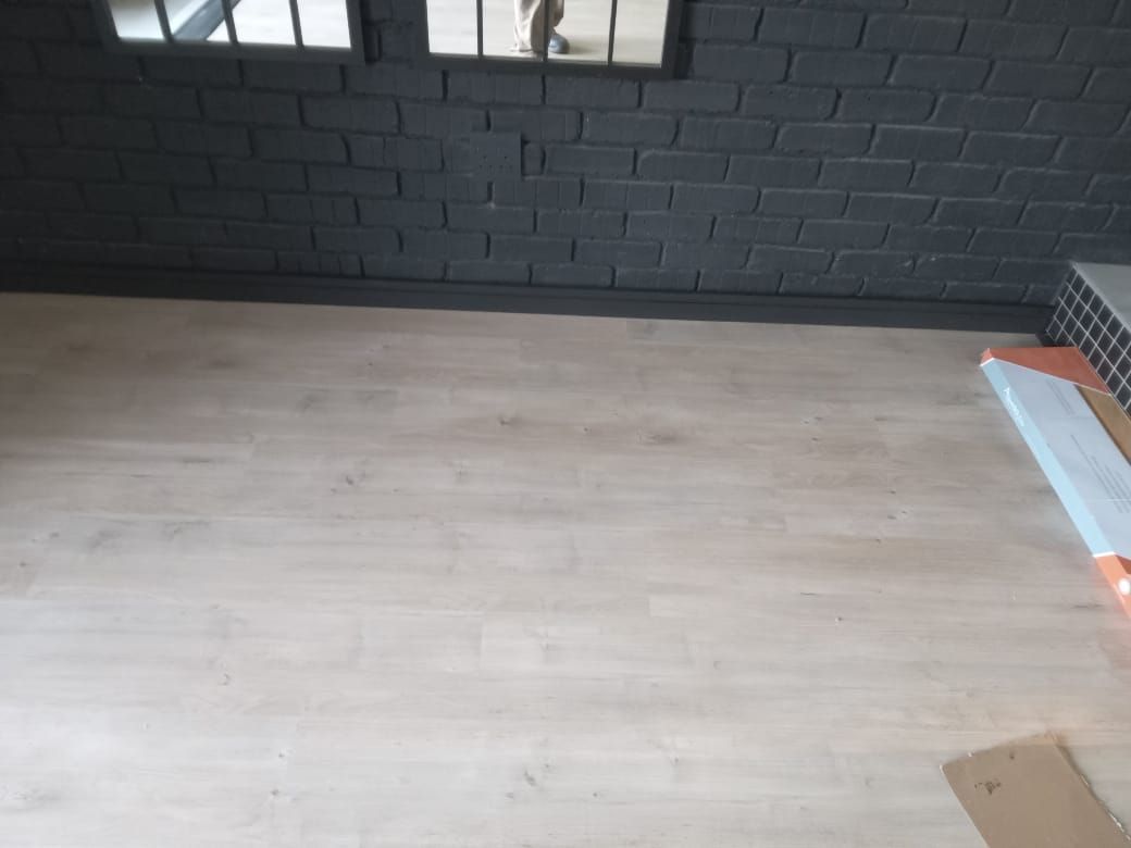 A room with a wooden floor and a black brick wall.