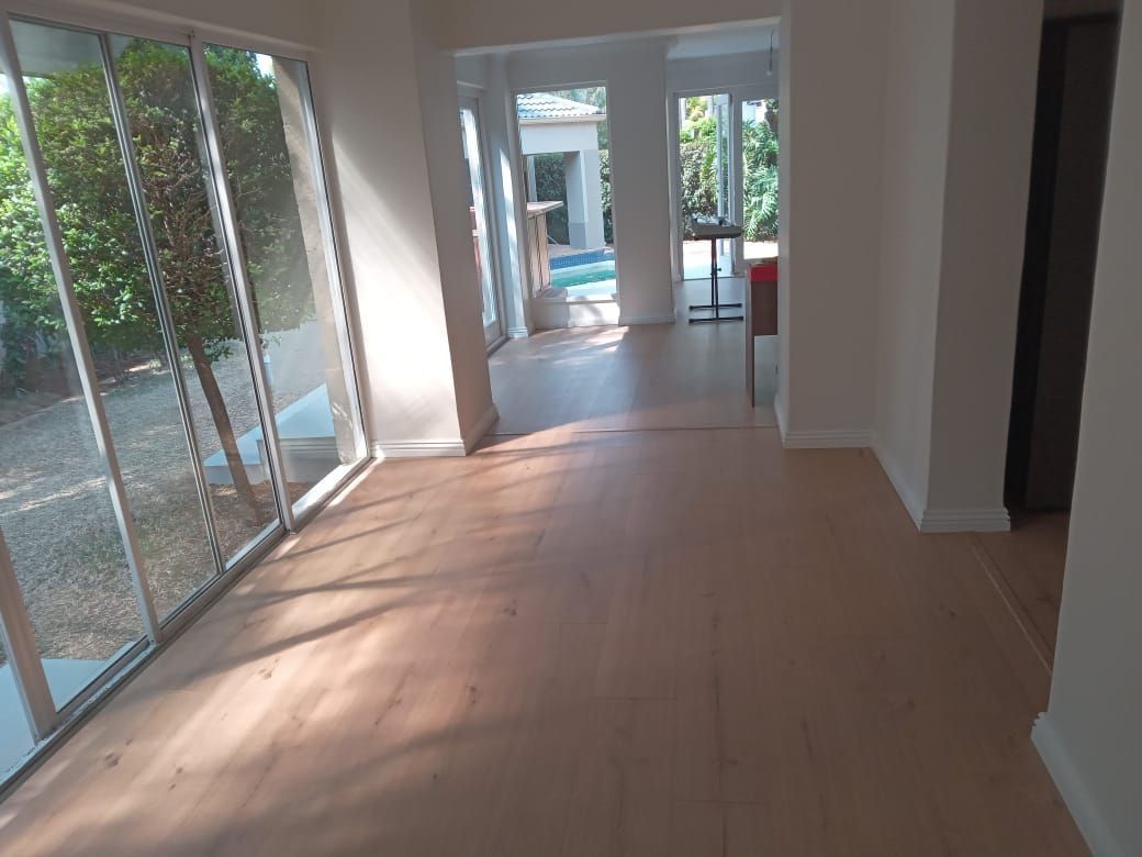 An empty room with hardwood floors and sliding glass doors.