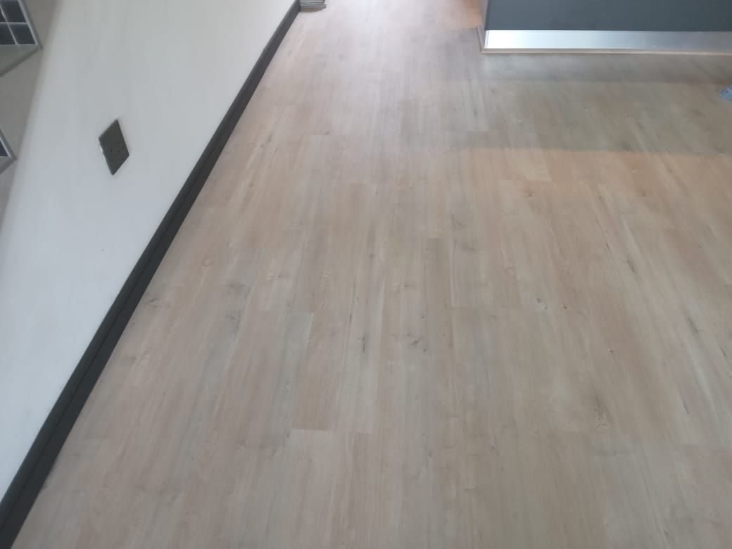 A wooden floor in a room with a white wall.