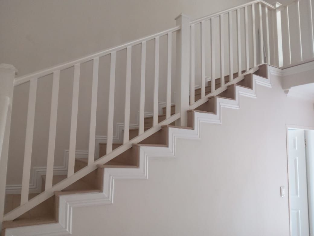 A white staircase with a white railing in a room.