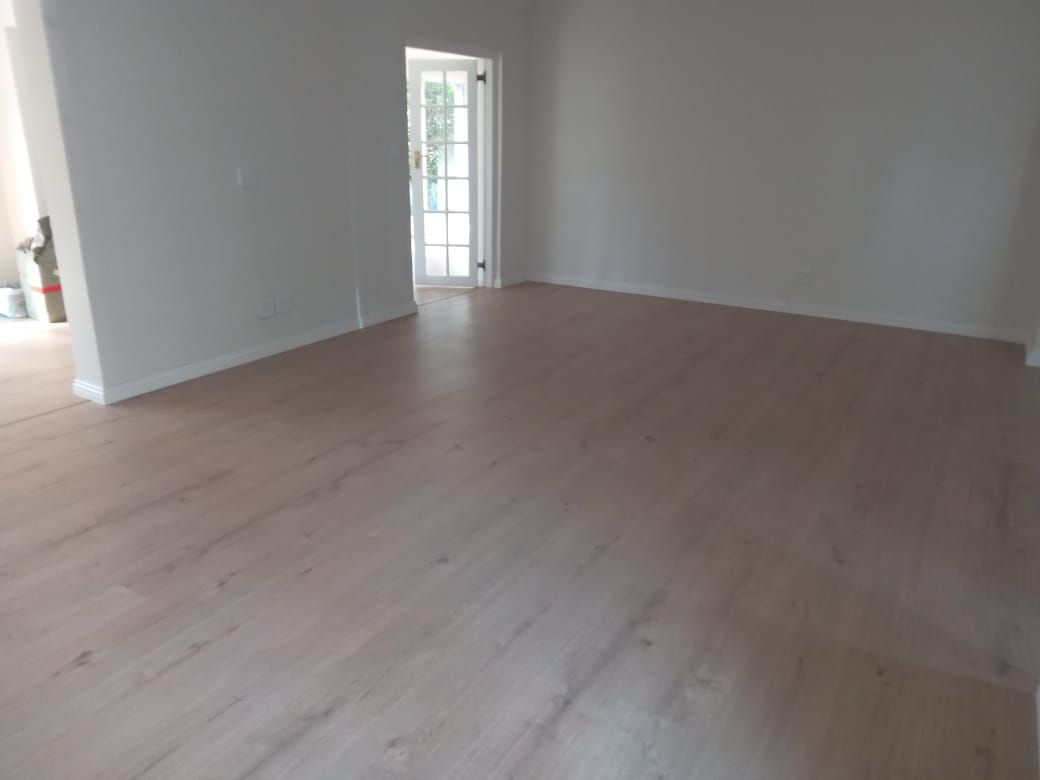 An empty living room with hardwood floors and white walls.