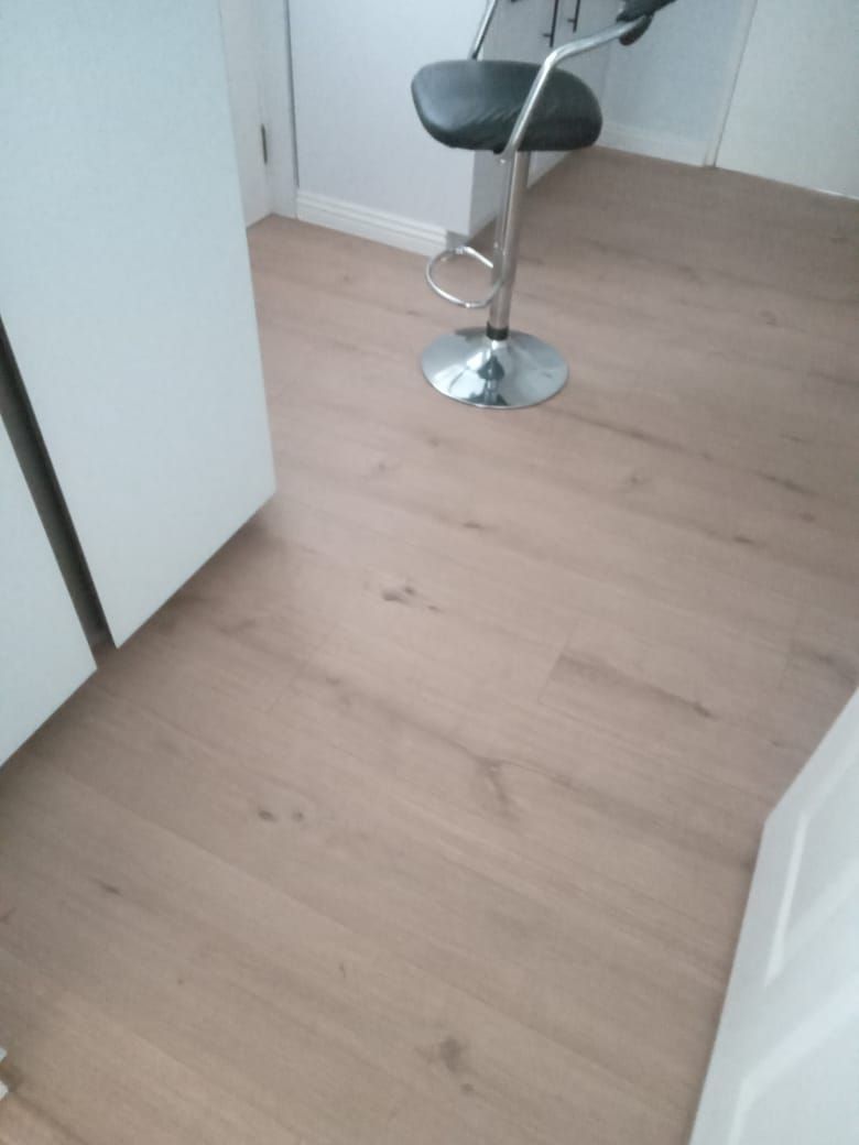 A bar stool is sitting on a wooden floor in a kitchen.