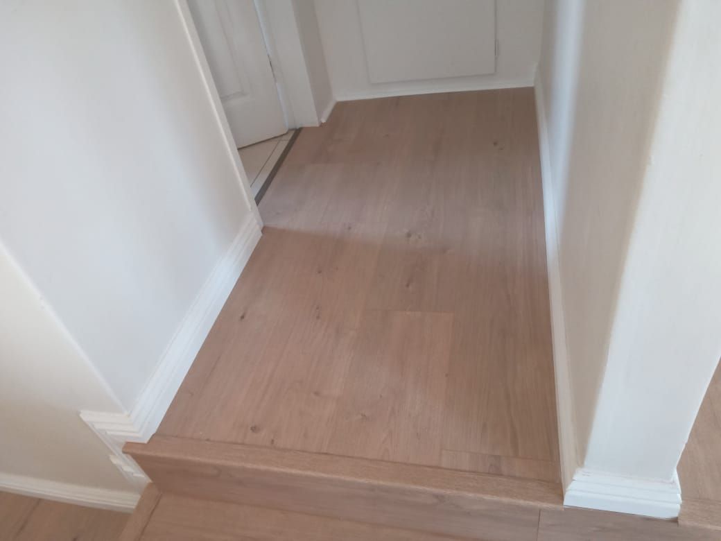 A hallway with a wooden floor and white walls