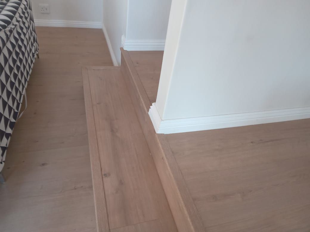 A bedroom with a bed and a wooden floor.