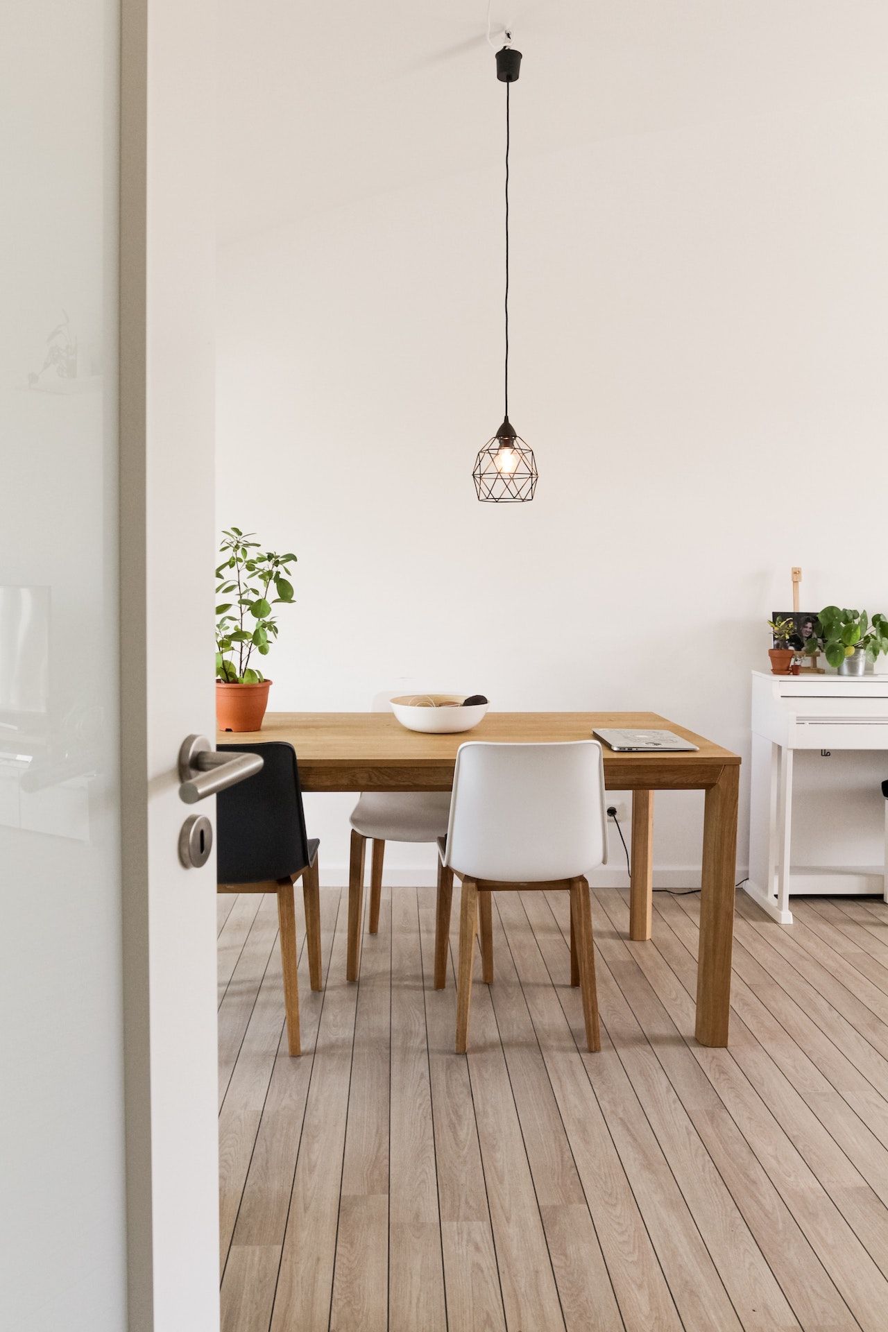 A dining room with a wooden table and white chairs.