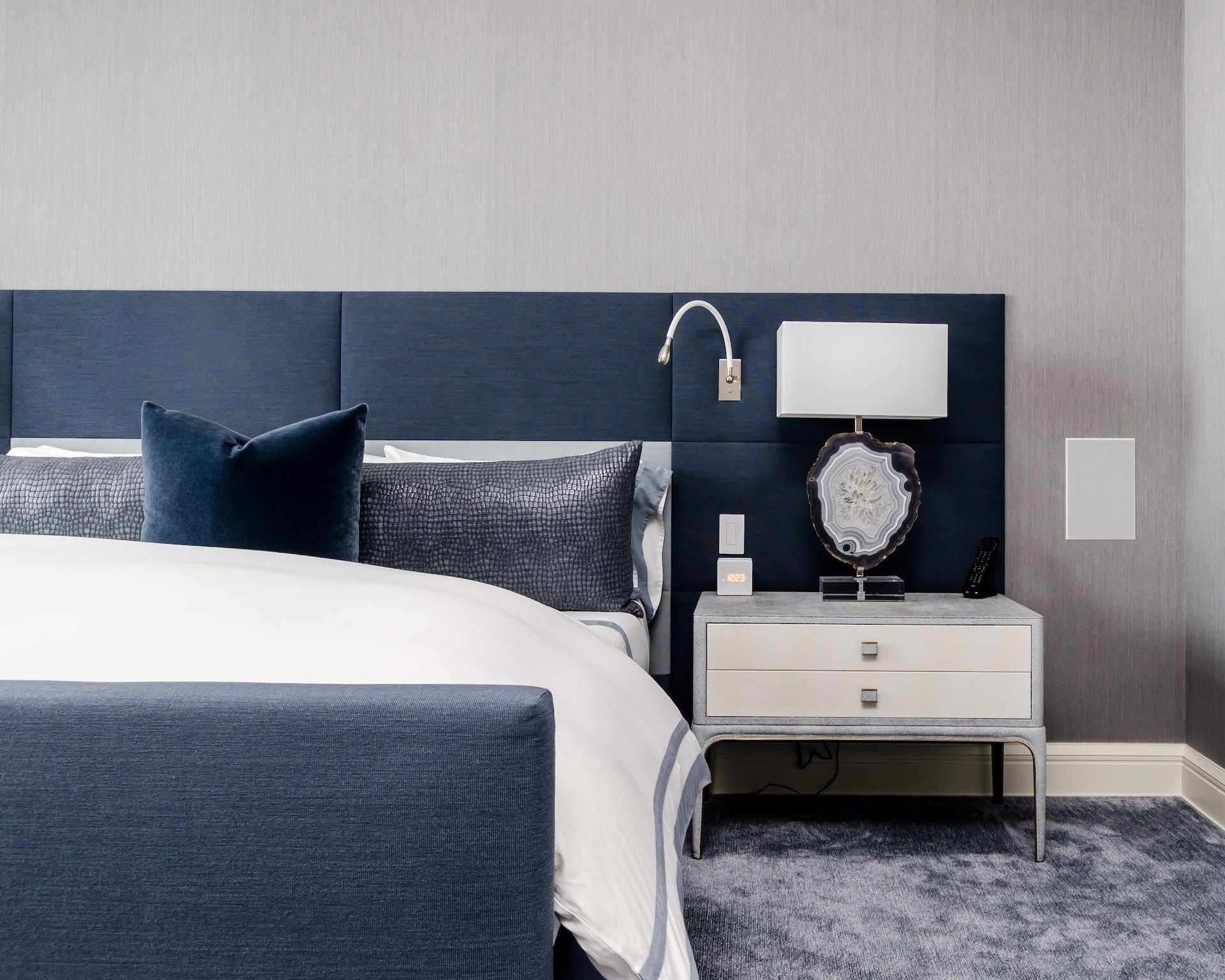 A bedroom with a bed , nightstand and lamp