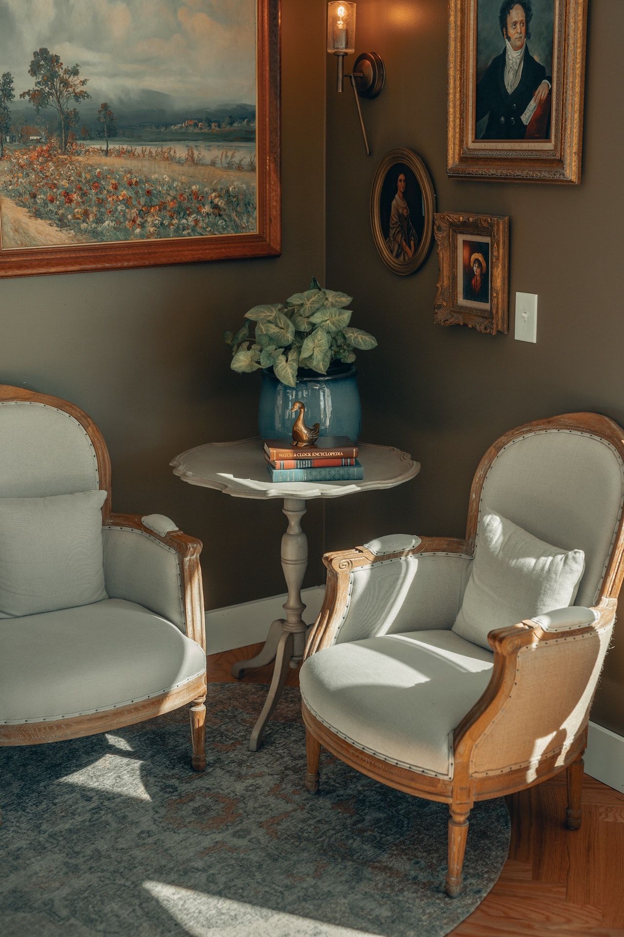 A living room with two chairs , a table and a painting on the wall.