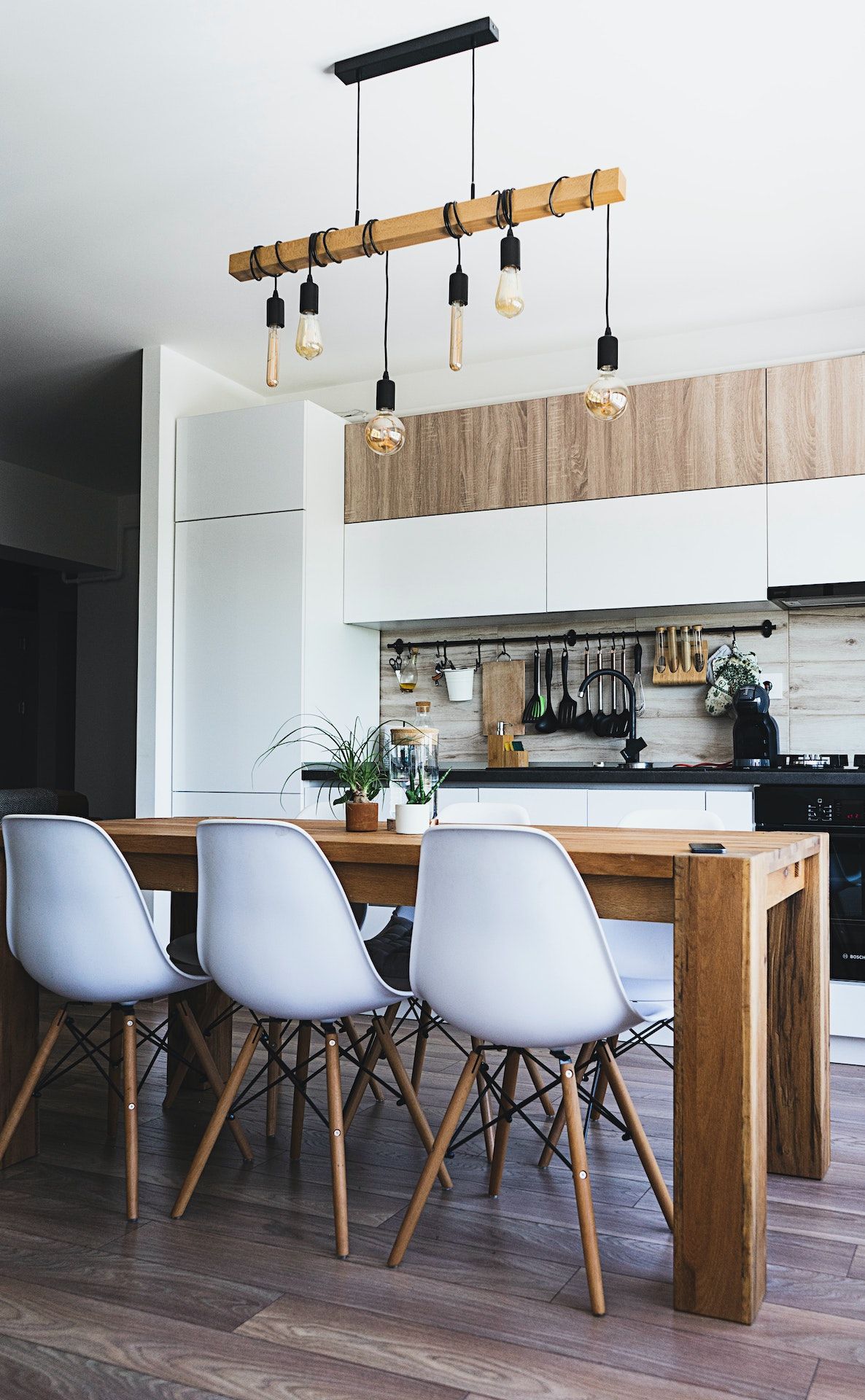 A kitchen with a wooden table and white chairs.