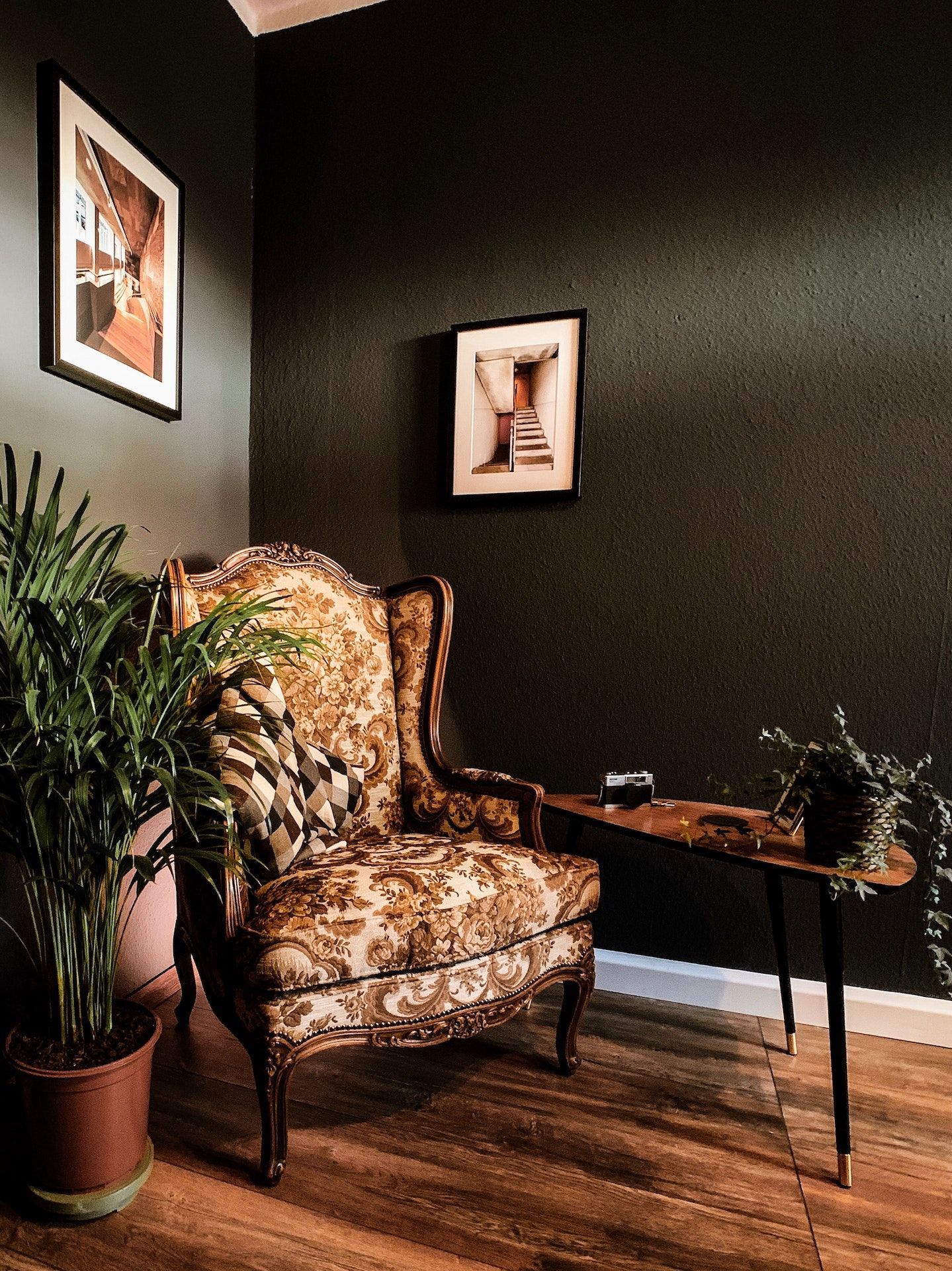 A chair is sitting in a corner of a room next to a table.