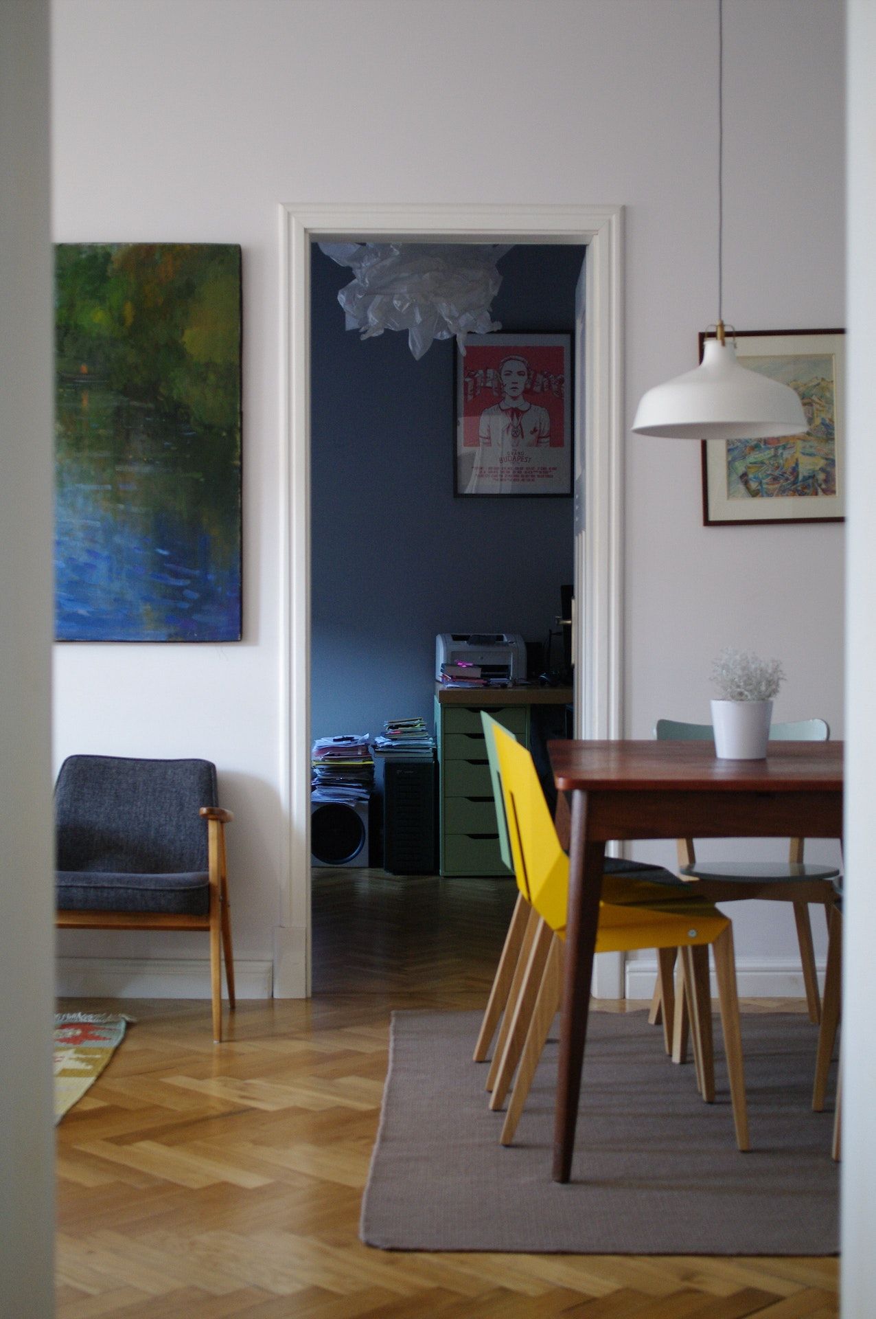 A dining room with a table and chairs and a painting on the wall.