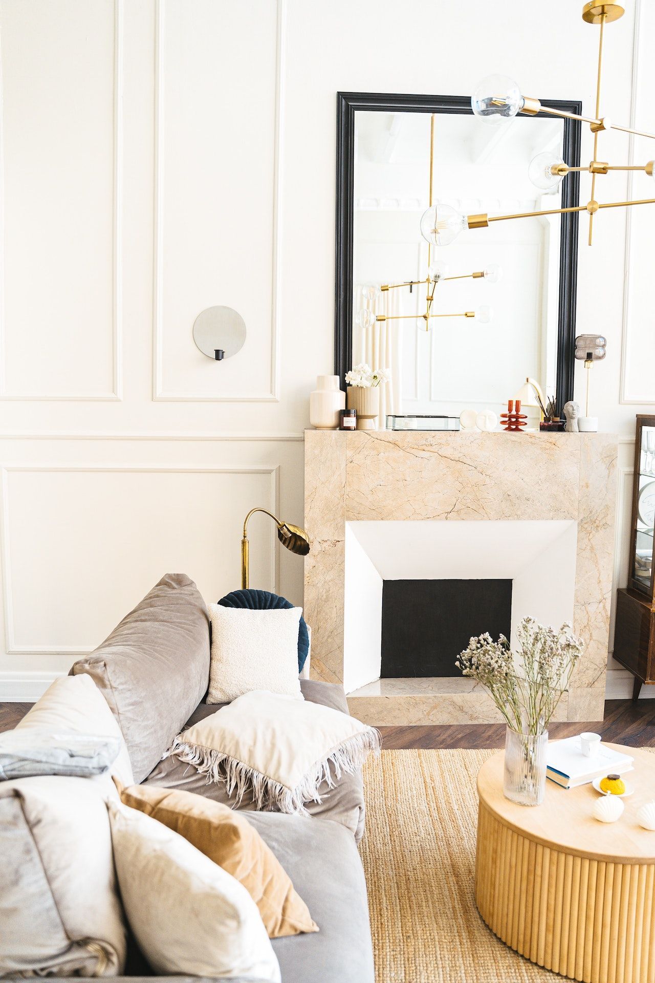 A living room with a couch , fireplace , coffee table and mirror.