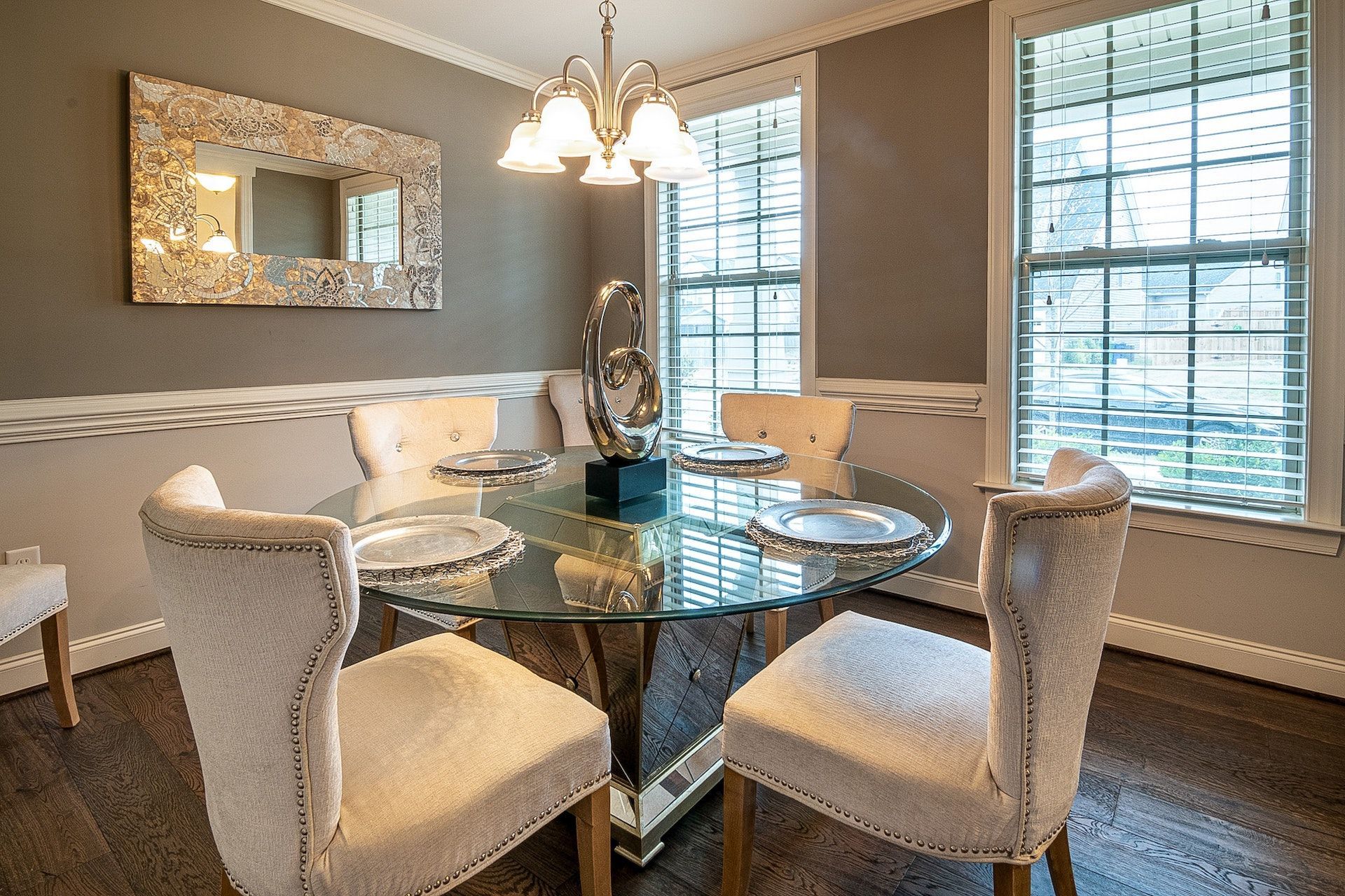 A dining room with a glass table and white chairs.