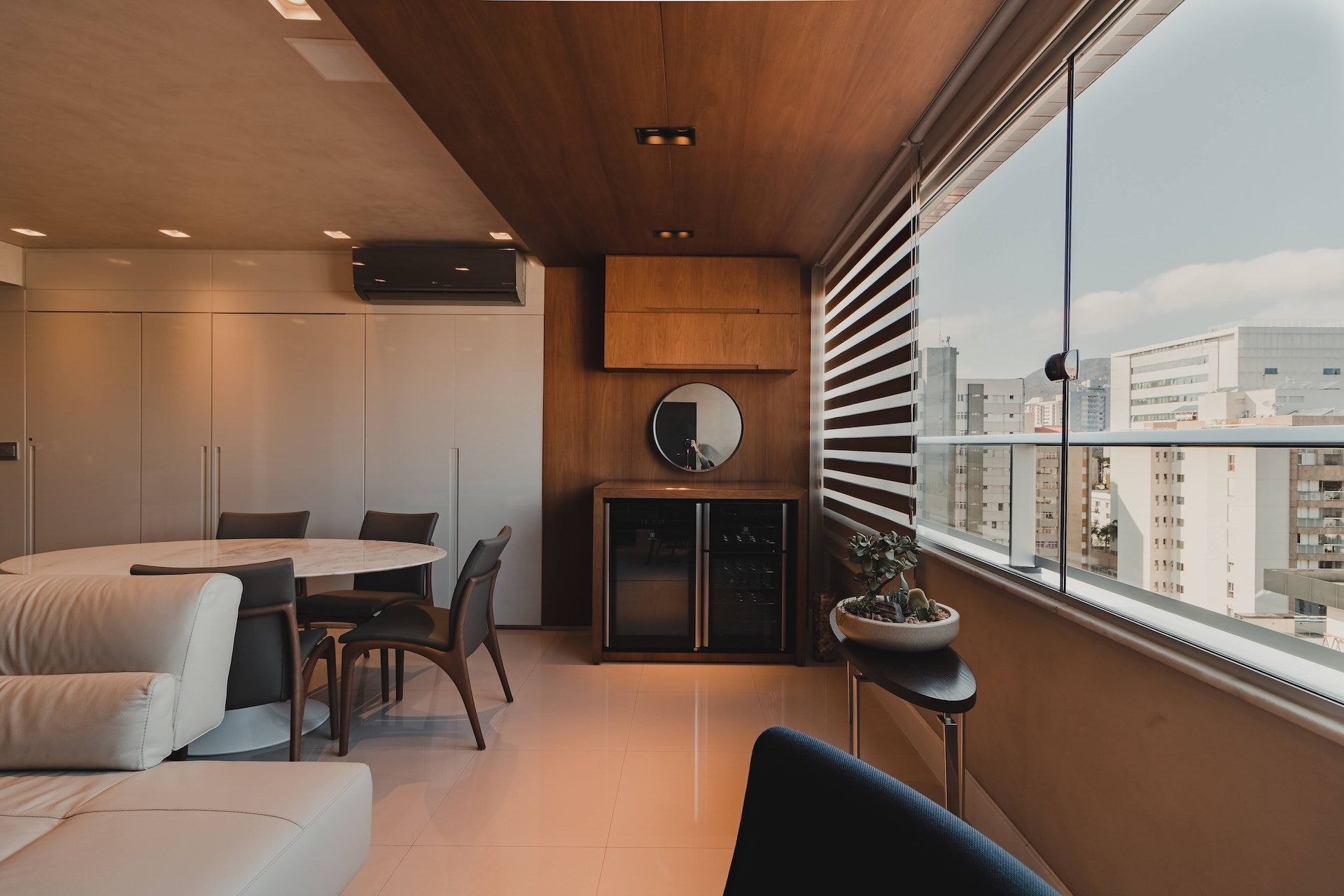 A living room with a table and chairs and a balcony with a view of the city.