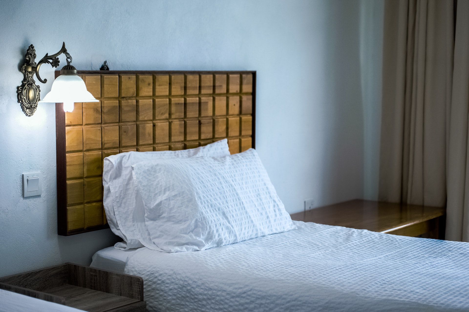 A hotel room with two beds and a lamp on the wall