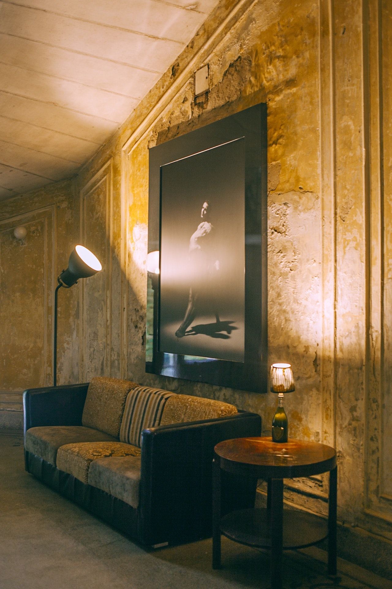 A living room with a couch , table , lamp and a large picture on the wall.
