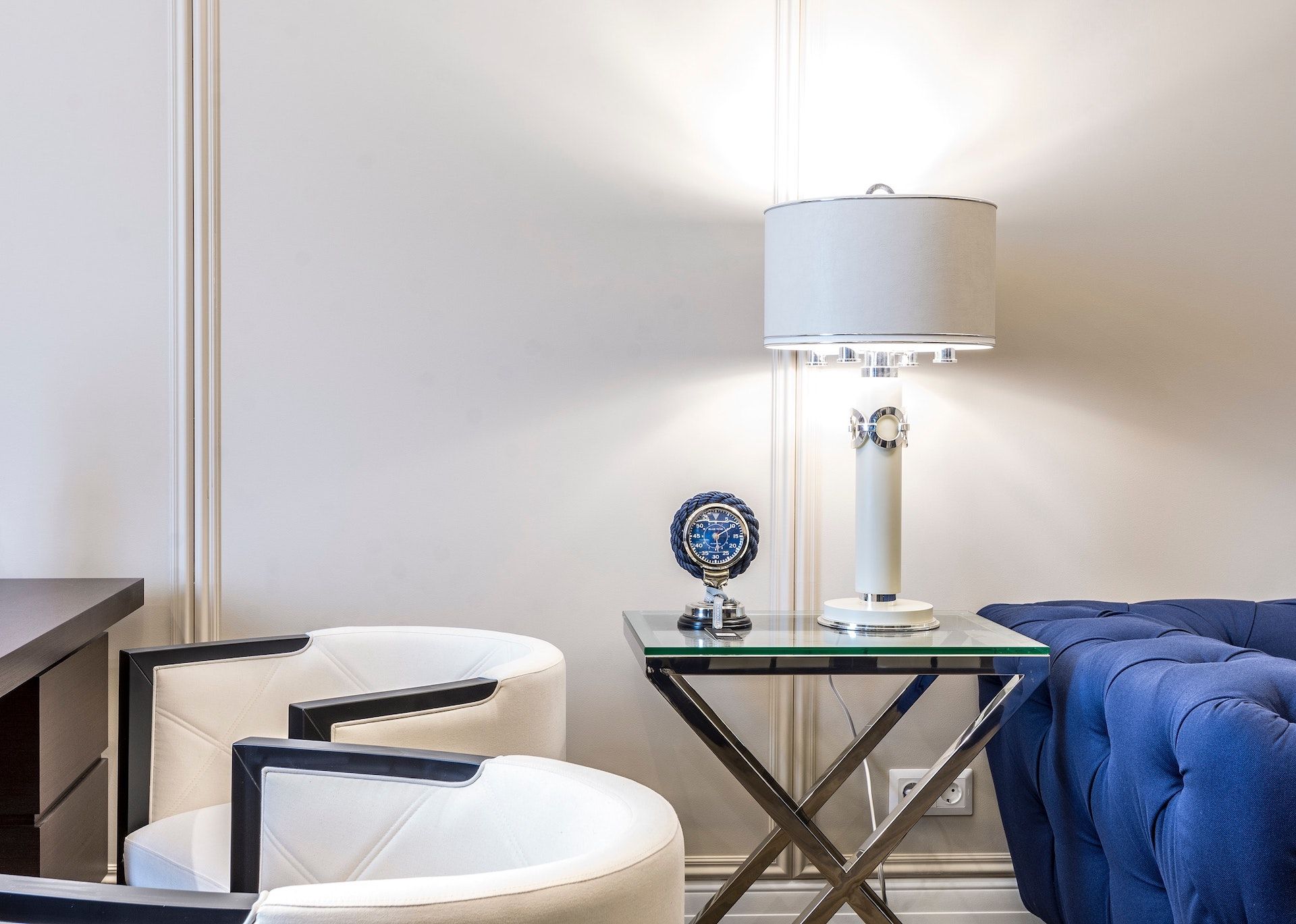 A living room with two chairs , a lamp , and a blue couch.