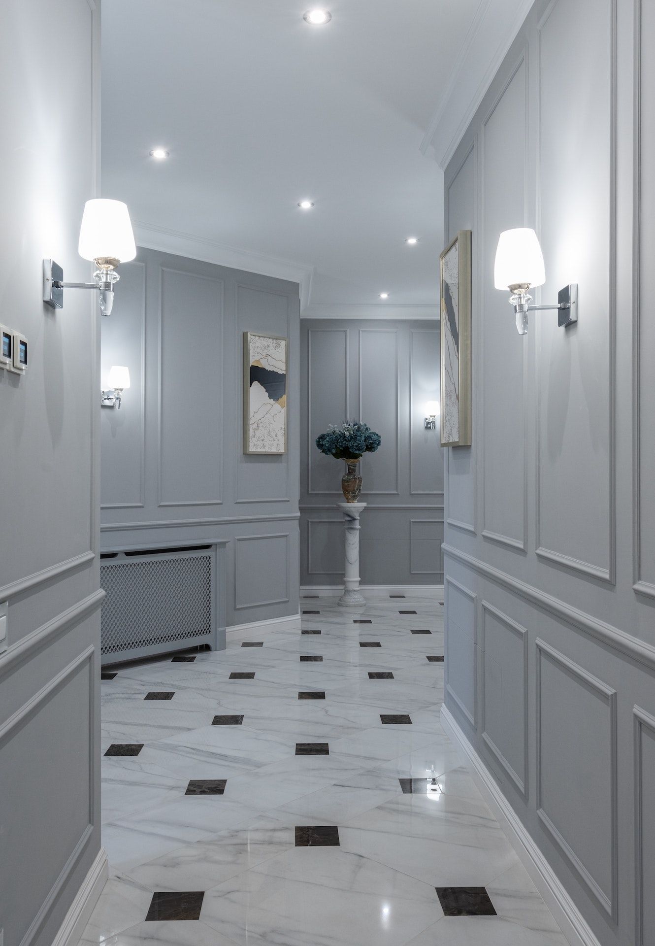 A hallway with gray walls and a black and white tile floor.