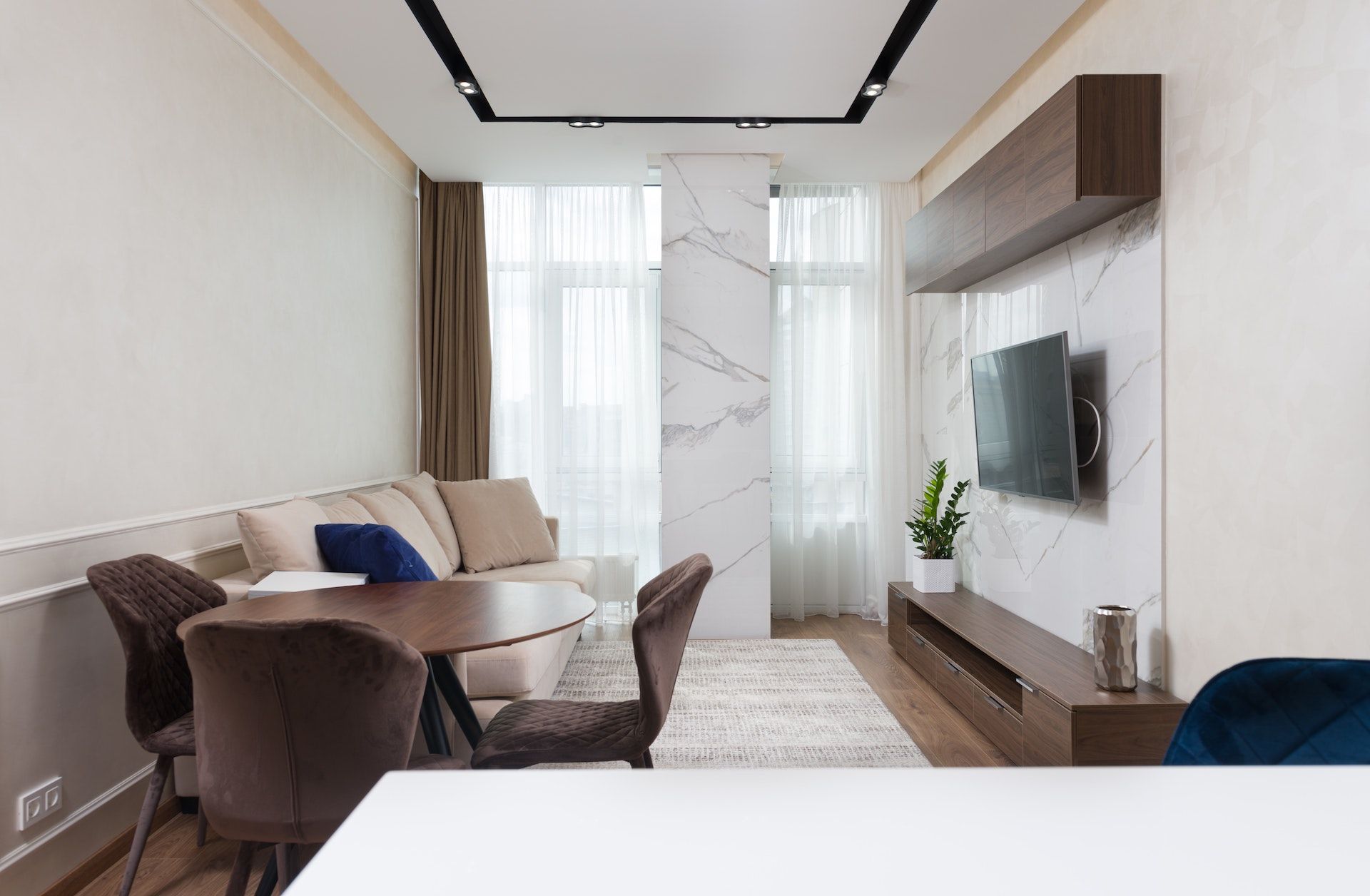 A living room with a couch , table , chairs and a flat screen tv.