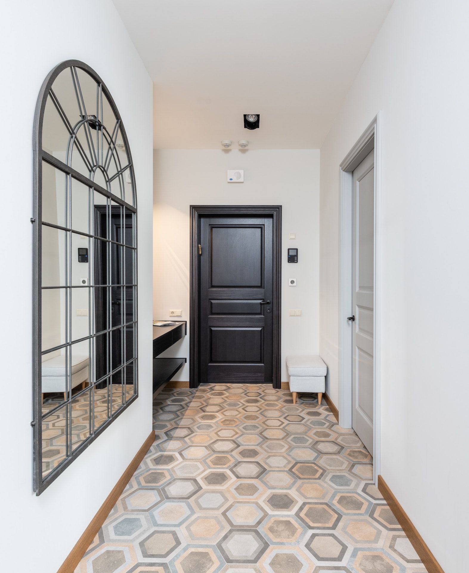 A hallway with a black door and a mirror on the wall