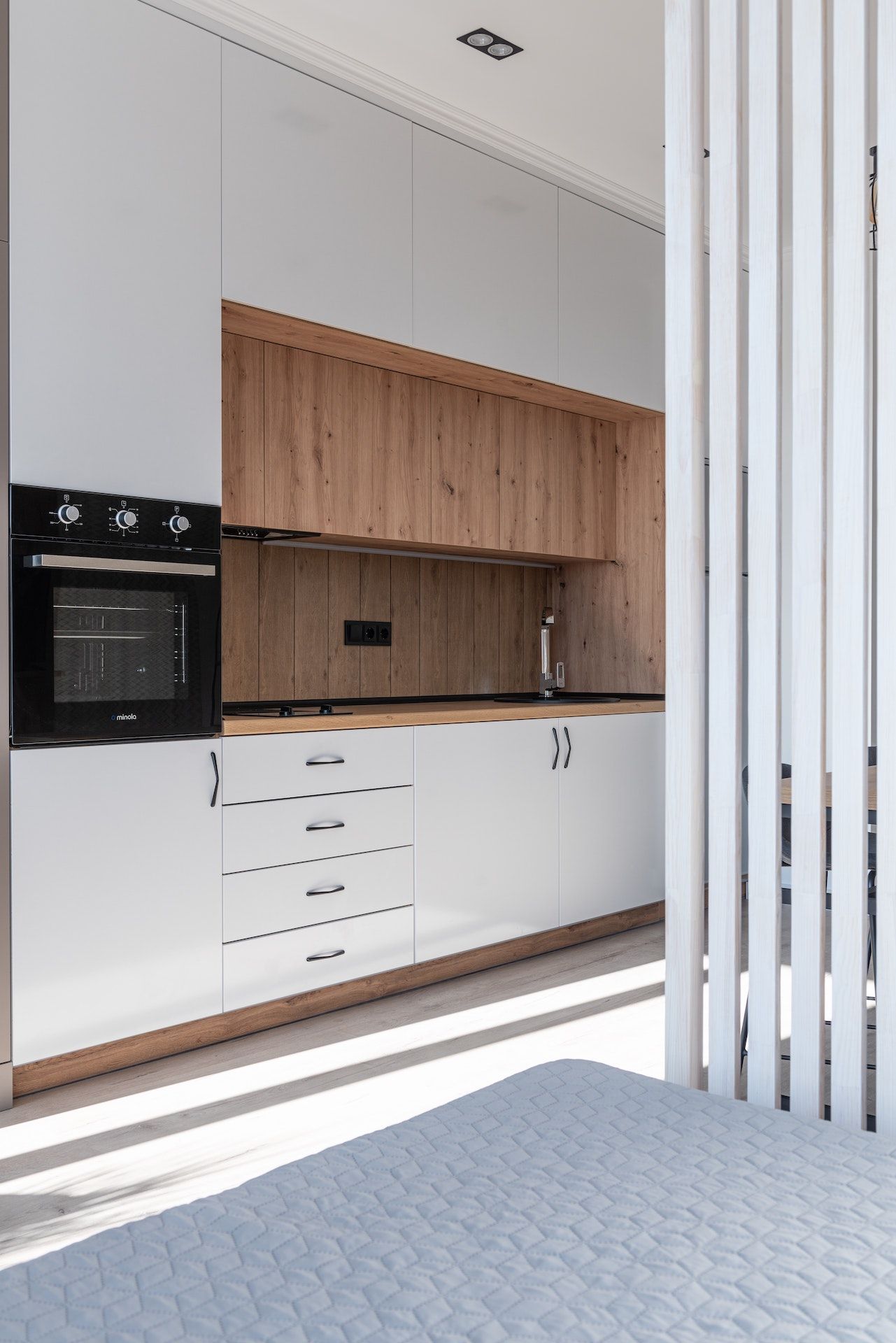 A kitchen with white cabinets , wooden cabinets , and a black oven.