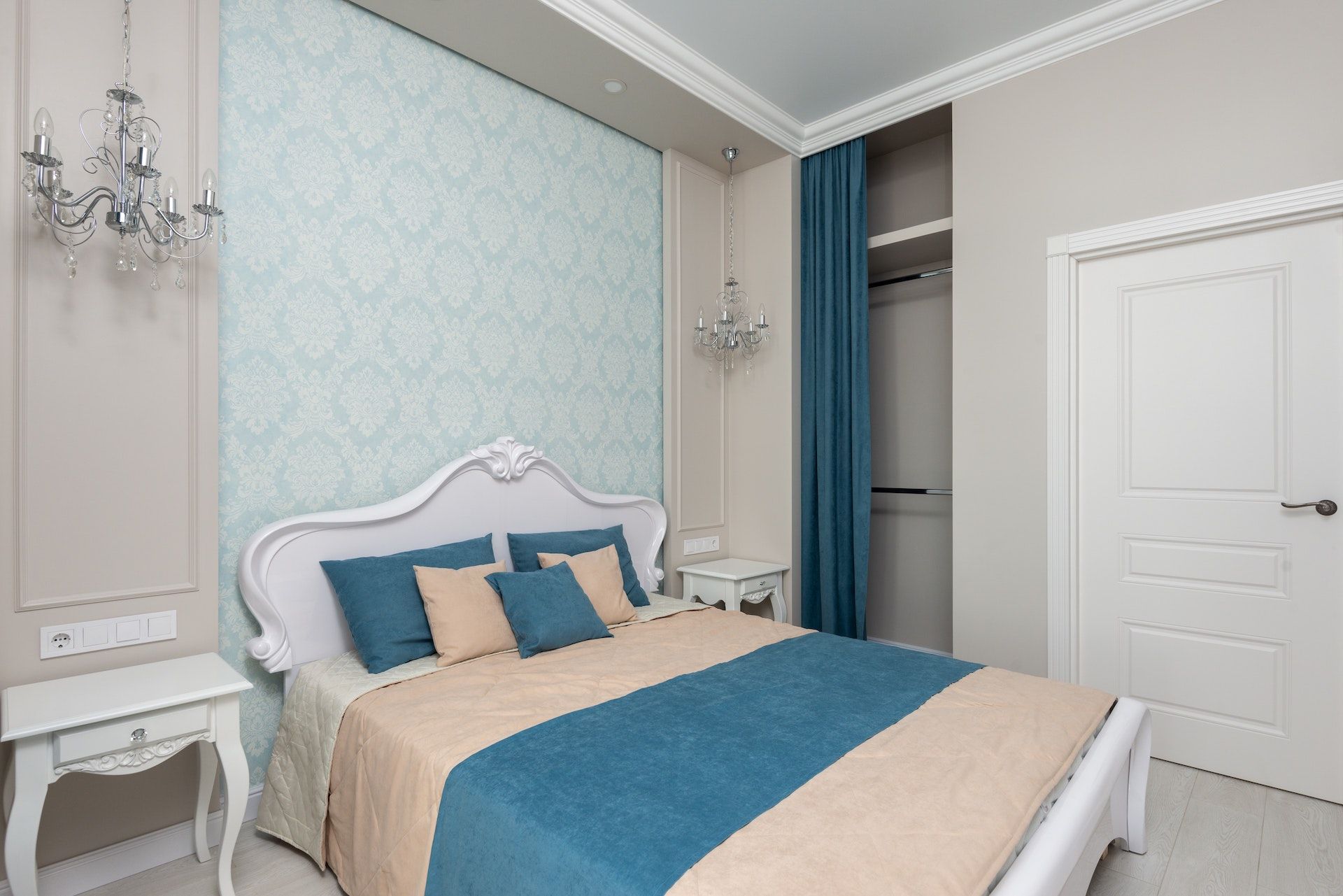 A bedroom with a bed , nightstand , and chandelier.