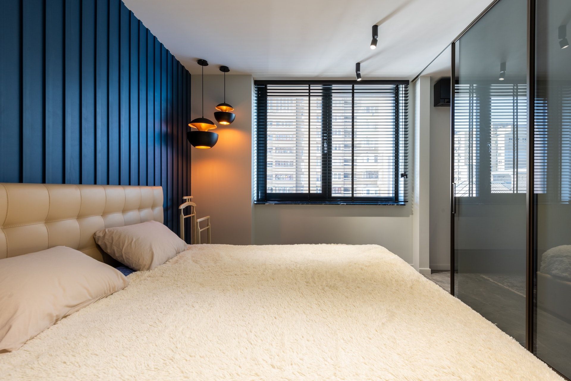 A bedroom with a bed and a window with blinds.