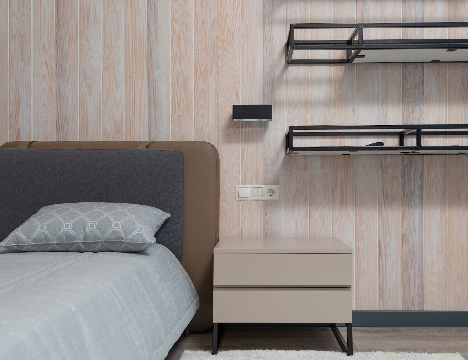 A bedroom with a bed , nightstand , and shelves.