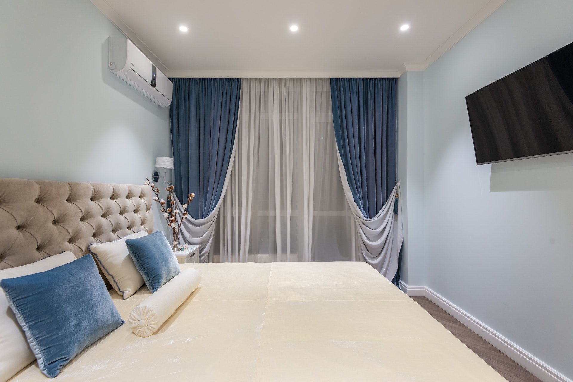A bedroom with a bed , curtains and a television.