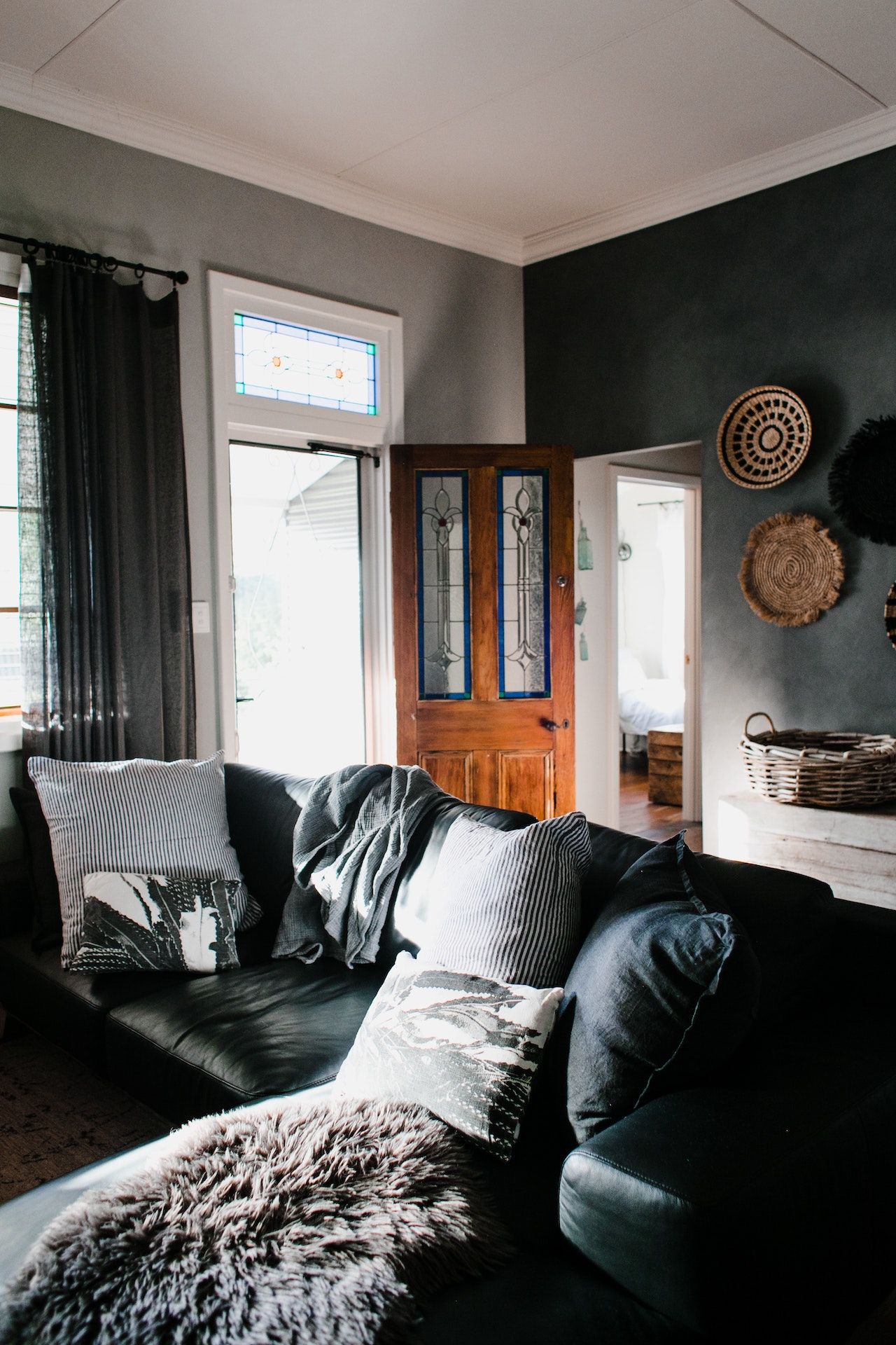 A living room with a black couch and a brown door.