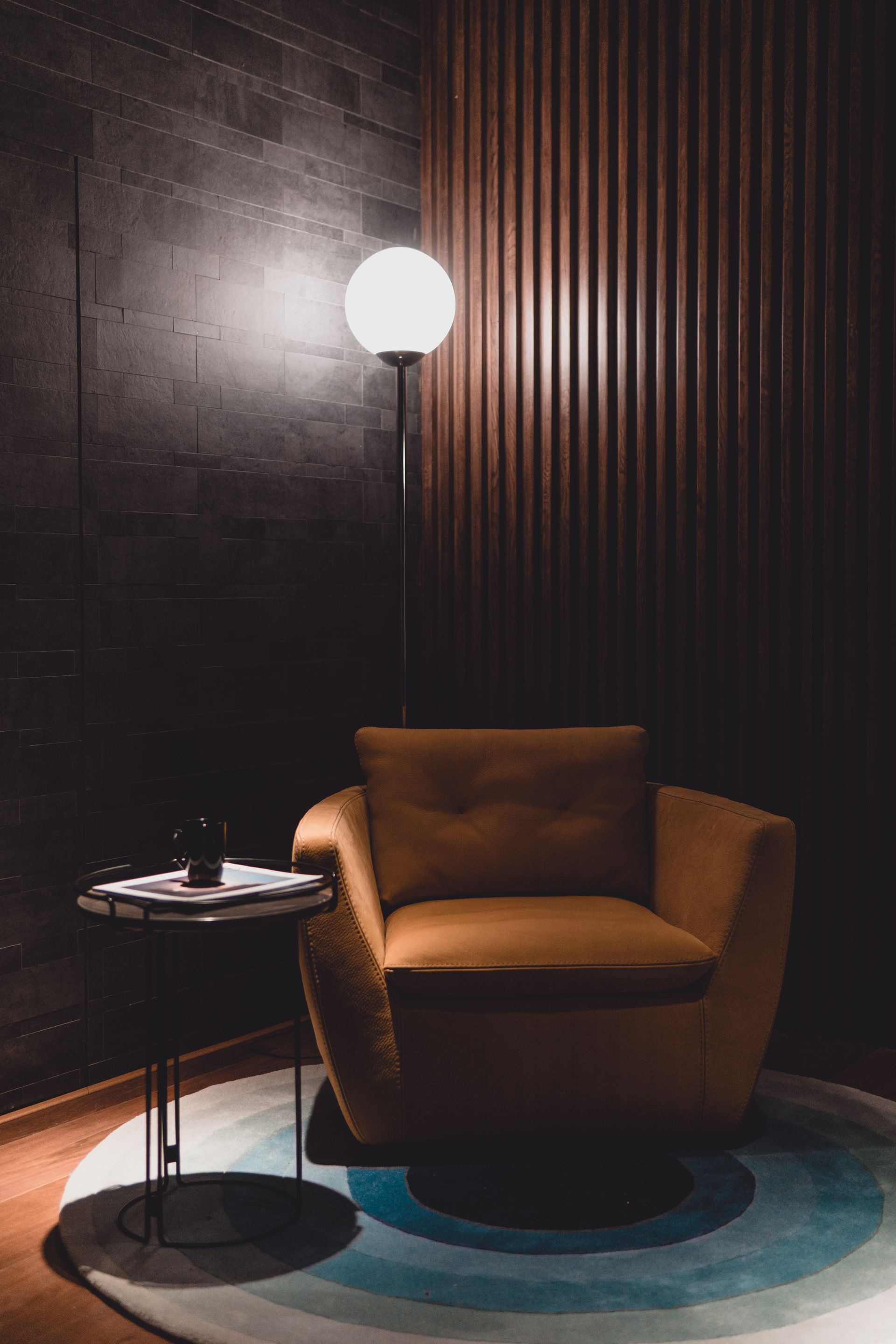 A chair and a table in a dark room with a lamp.