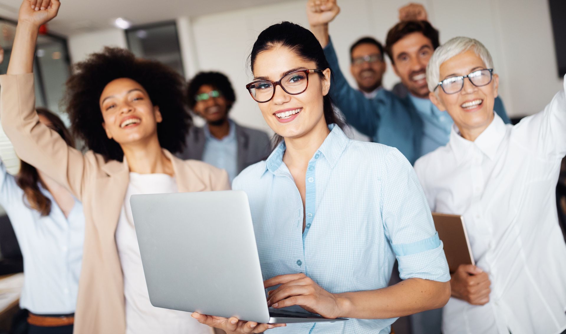 a woman is holding a laptop computer in front of a group of people